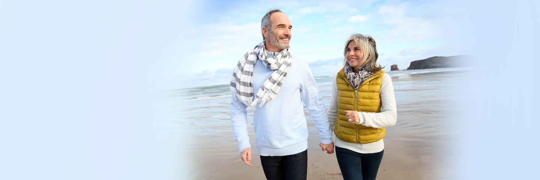 Older couple walking on a beach l Dentures Doylestown PA
