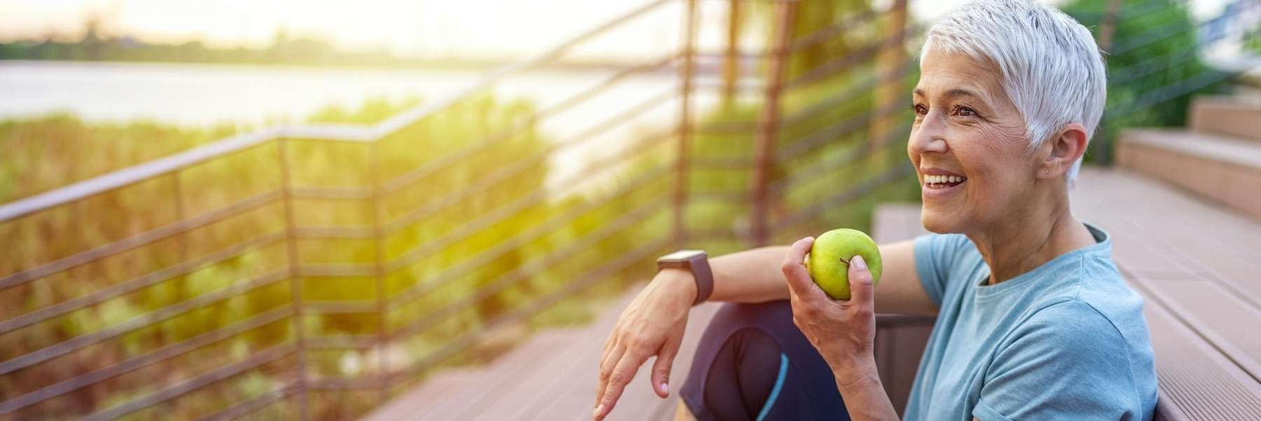 White haired woman eating apple with her restored teeth in Doylestown