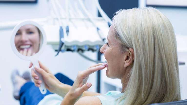 Woman patient in Doylestown PA checking her reconstructed teeth