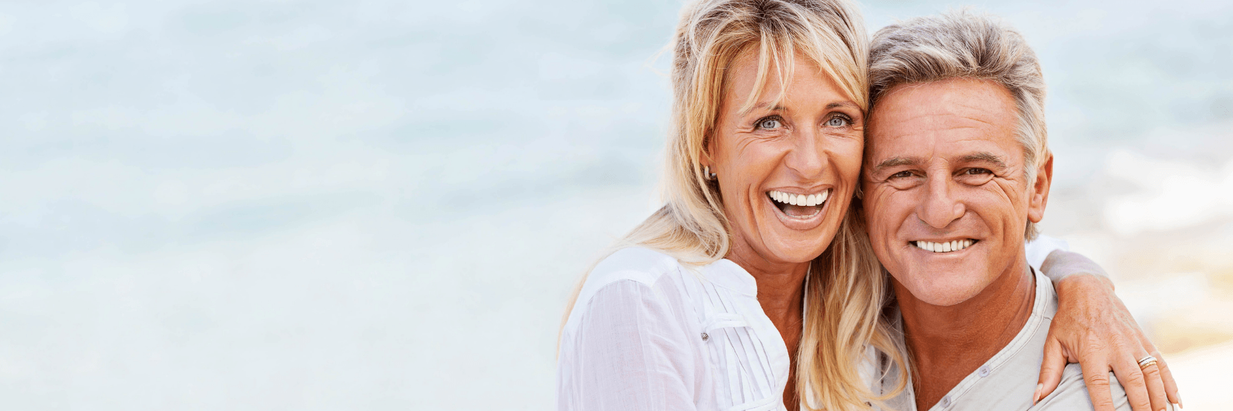 Older couple smiling on a beach l Dental Bridges Doylestown Dental Group